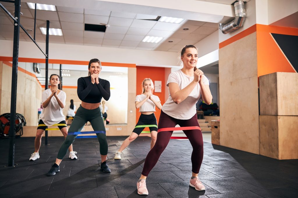 Cheerful young ladies working out and using fitness bands