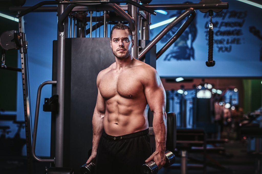 Shirtless bodybuilder in a modern fitness club