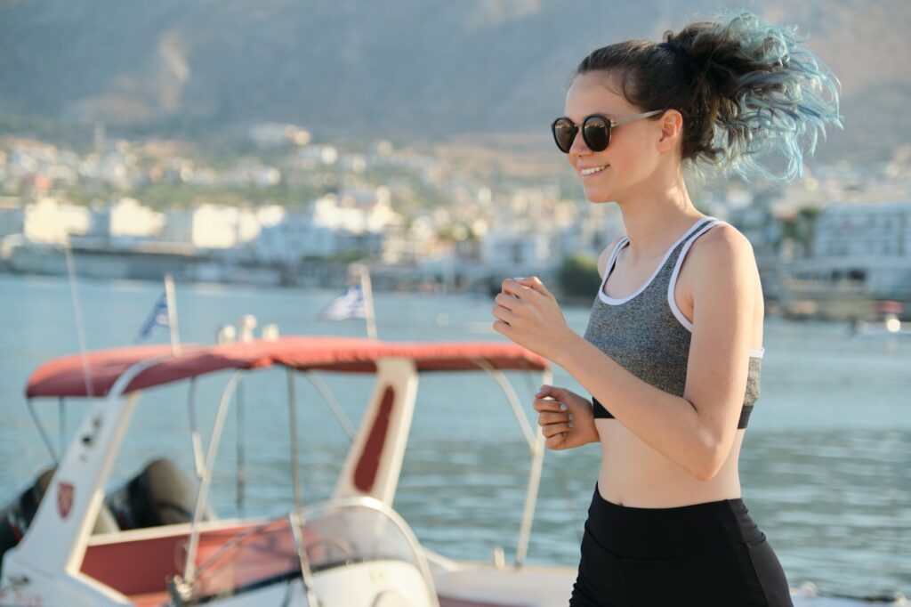Teen girl exercising outdoor, jogging running at seaside promenade