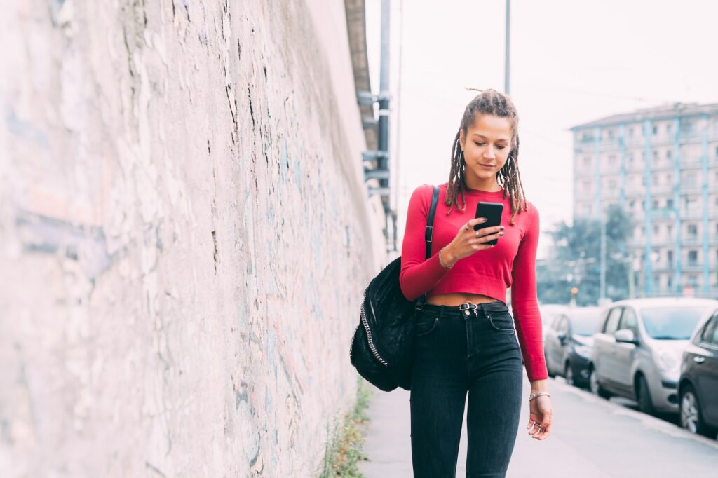 young woman walking outdoors using smartphone